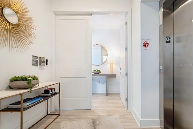 hallway featuring elevator and light hardwood / wood-style flooring