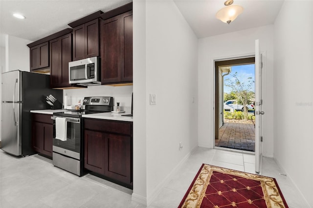 kitchen featuring dark brown cabinetry, stainless steel appliances, and light tile patterned floors