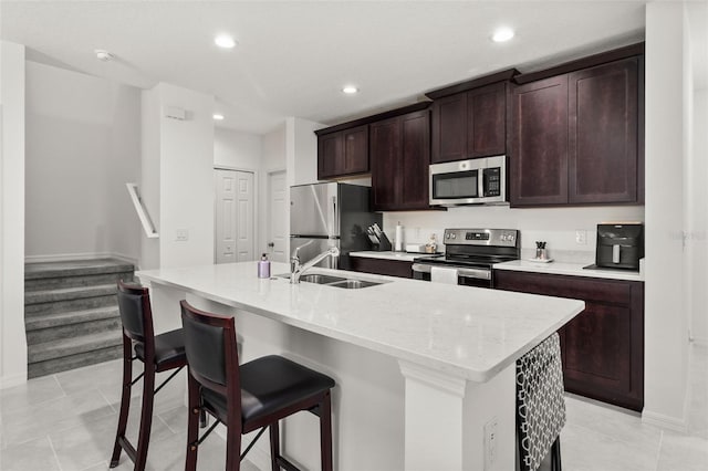 kitchen with stainless steel appliances, a center island with sink, sink, and a breakfast bar