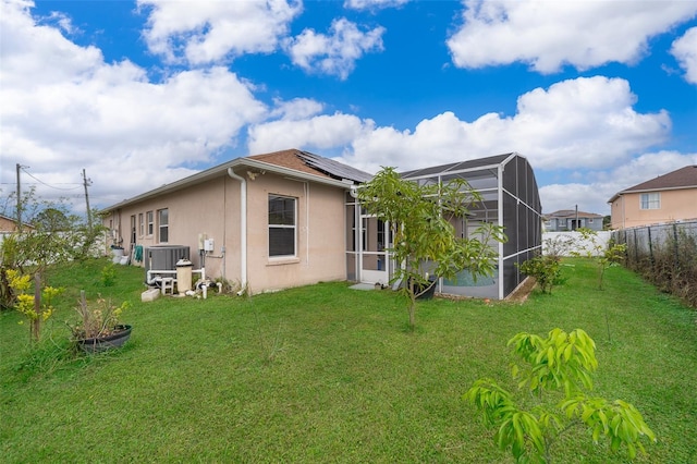 rear view of property featuring a lawn, a lanai, and cooling unit