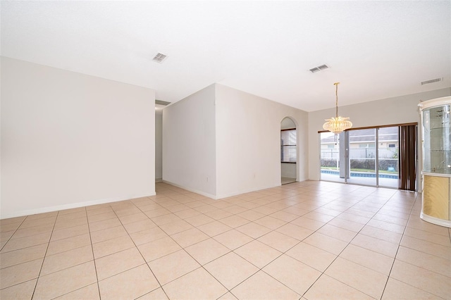 tiled empty room featuring a notable chandelier