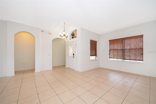 tiled empty room featuring a chandelier