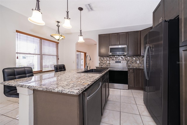 kitchen featuring tasteful backsplash, appliances with stainless steel finishes, sink, a breakfast bar, and a kitchen island with sink