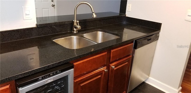 kitchen featuring dark stone countertops, sink, beverage cooler, and stainless steel dishwasher