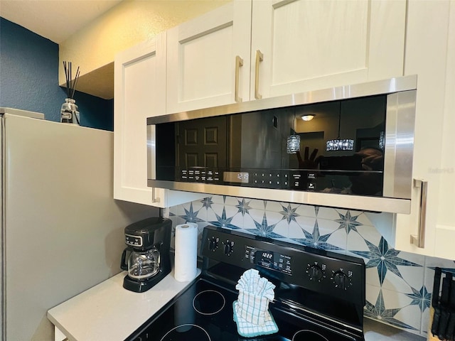 kitchen featuring tasteful backsplash, white cabinetry, and black electric range