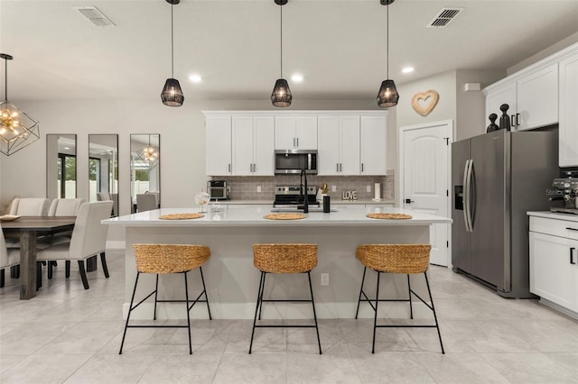 kitchen featuring a kitchen island with sink, pendant lighting, and appliances with stainless steel finishes