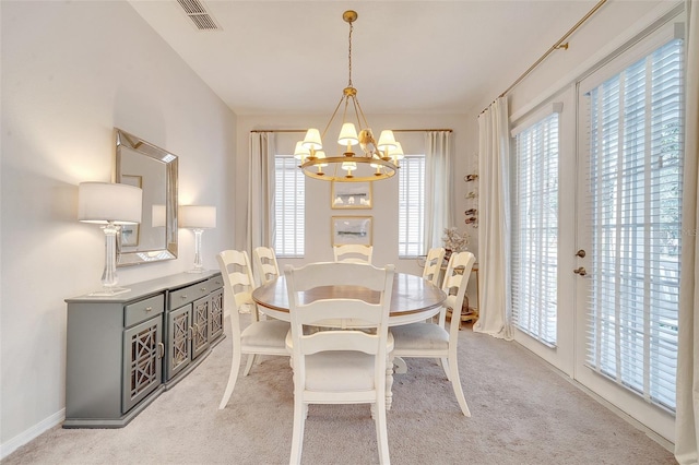 carpeted dining room with an inviting chandelier and plenty of natural light