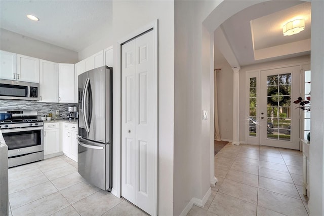 kitchen with white cabinetry, decorative backsplash, appliances with stainless steel finishes, and light tile patterned floors