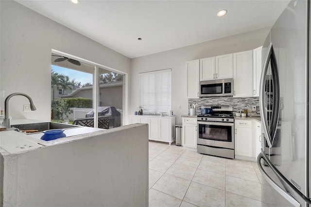 kitchen featuring white cabinetry, appliances with stainless steel finishes, decorative backsplash, and light stone counters