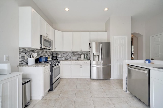 kitchen with white cabinetry, decorative backsplash, light tile patterned floors, and stainless steel appliances