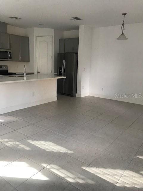 kitchen featuring pendant lighting, black fridge with ice dispenser, stove, and sink