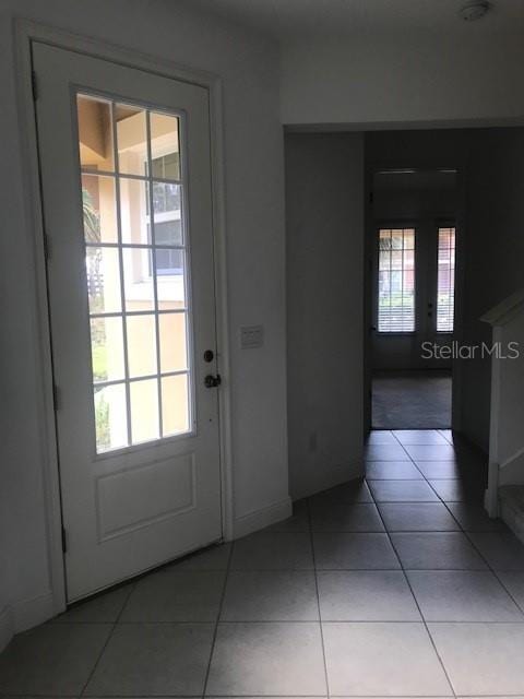 doorway to outside featuring light tile patterned floors and a healthy amount of sunlight