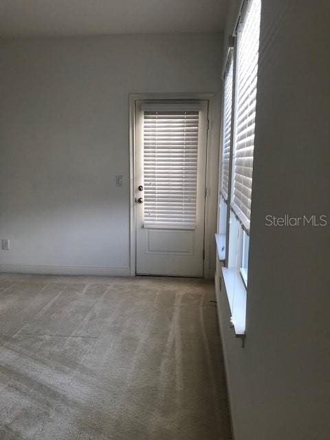 doorway to outside featuring plenty of natural light and carpet