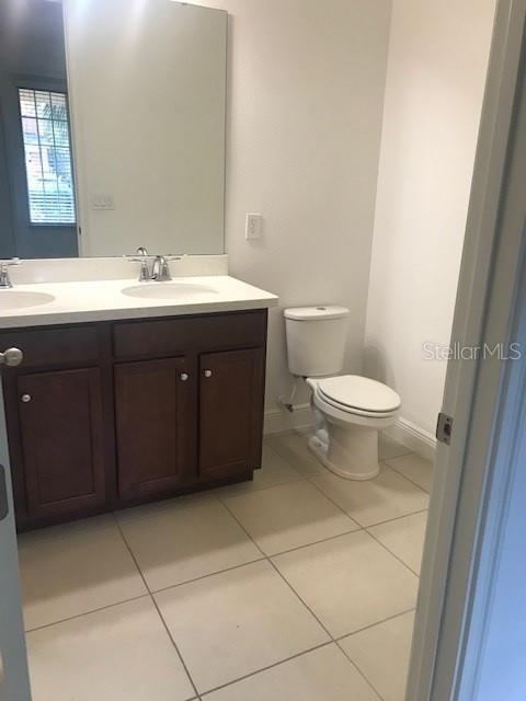 bathroom with toilet, vanity, and tile patterned flooring