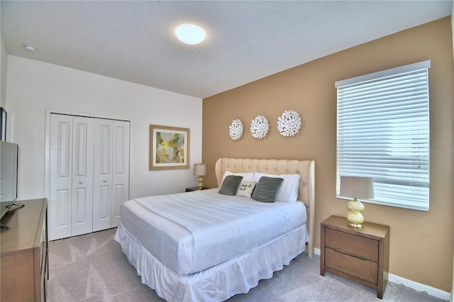 carpeted bedroom featuring a textured ceiling and a closet