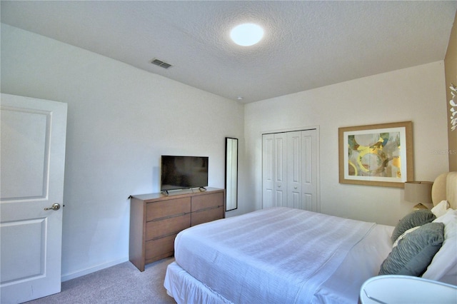 bedroom featuring a closet, a textured ceiling, and light carpet