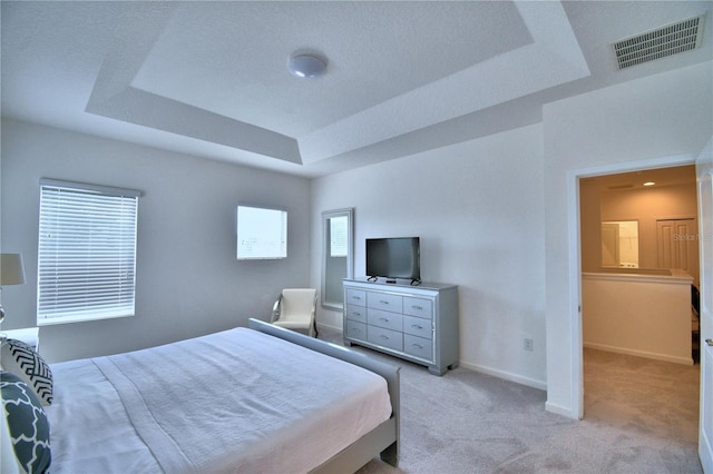 carpeted bedroom with a tray ceiling and multiple windows