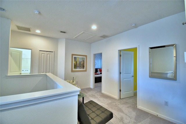 hall featuring a textured ceiling and light carpet