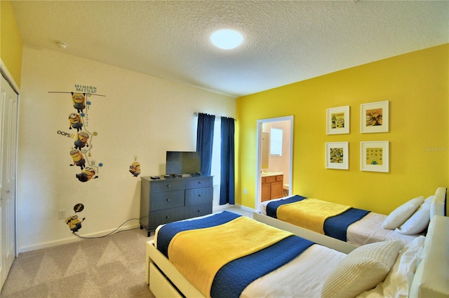 carpeted bedroom with ensuite bathroom and a textured ceiling