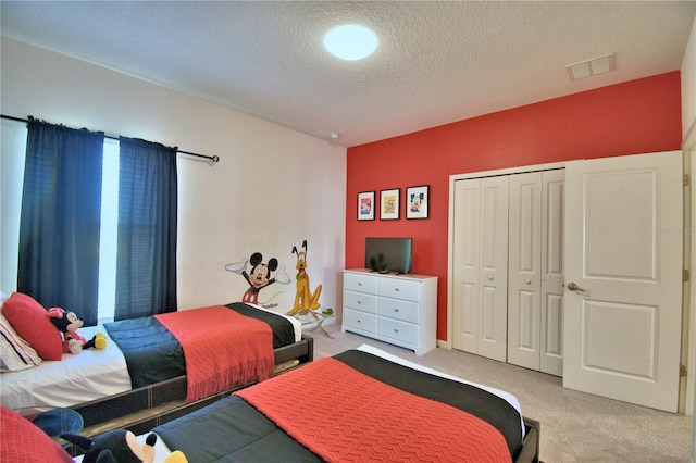 bedroom with a textured ceiling, a closet, and carpet