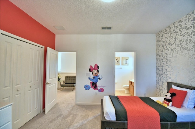 carpeted bedroom with a textured ceiling and ensuite bath