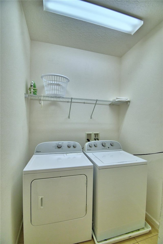 washroom featuring a textured ceiling, washer and clothes dryer, and light tile patterned floors