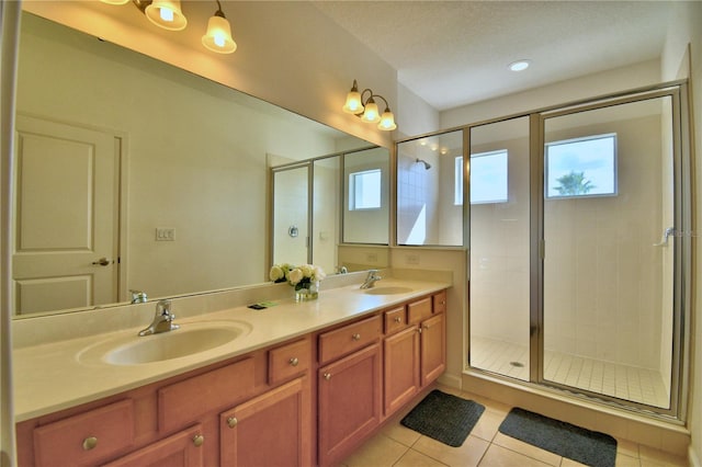 bathroom featuring vanity, a shower with shower door, tile patterned flooring, and a textured ceiling