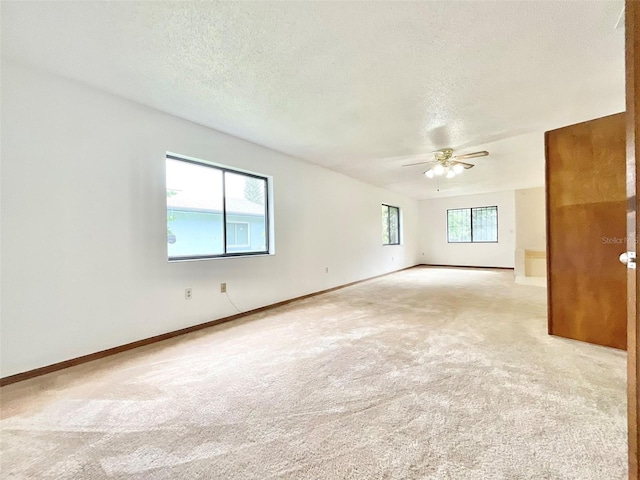 empty room with a textured ceiling, light colored carpet, and a healthy amount of sunlight