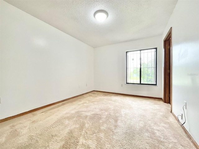 spare room with a textured ceiling and light colored carpet