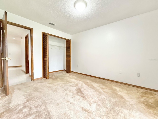 unfurnished bedroom featuring light colored carpet, a textured ceiling, and a closet