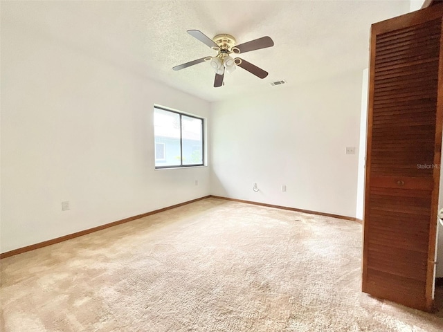 carpeted spare room featuring ceiling fan and a textured ceiling