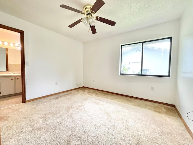 spare room with ceiling fan, a textured ceiling, and light carpet