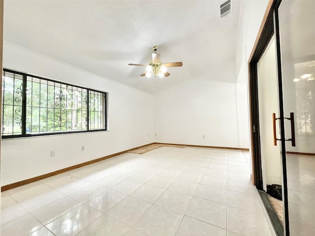 empty room with light tile patterned flooring, ceiling fan, and a textured ceiling