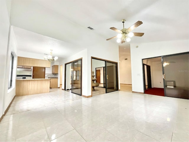 unfurnished living room featuring lofted ceiling, light tile patterned floors, and ceiling fan with notable chandelier