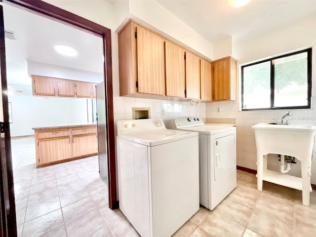 washroom with washing machine and dryer, cabinets, and light tile patterned flooring