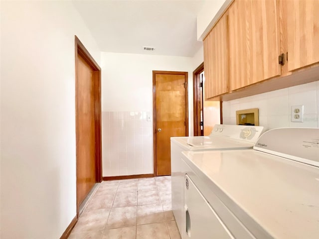 laundry area with cabinets, light tile patterned flooring, and washer and clothes dryer