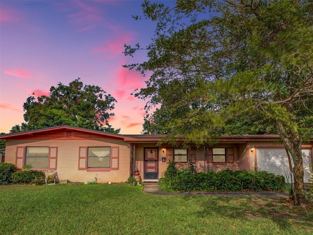 ranch-style home featuring a garage and a lawn