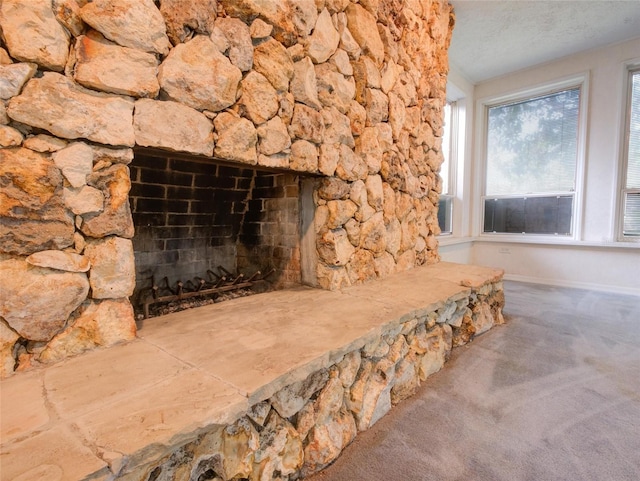 interior details featuring a stone fireplace, a textured ceiling, and carpet floors