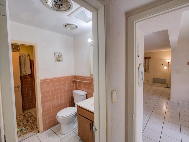 bathroom featuring a skylight, vanity, tile patterned floors, toilet, and tile walls