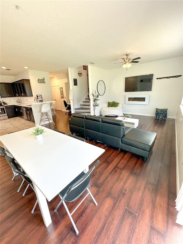 dining room featuring a textured ceiling, ceiling fan, and dark wood-type flooring