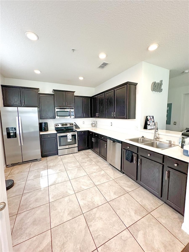 kitchen with sink, light tile patterned floors, a textured ceiling, and appliances with stainless steel finishes