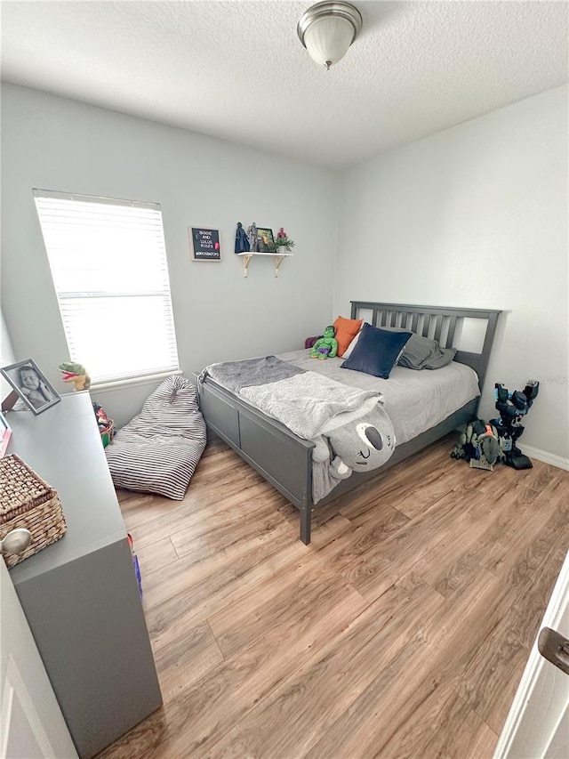 bedroom with a textured ceiling and light hardwood / wood-style flooring