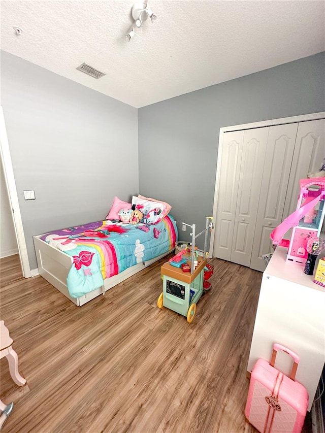 bedroom with wood-type flooring, a textured ceiling, and a closet