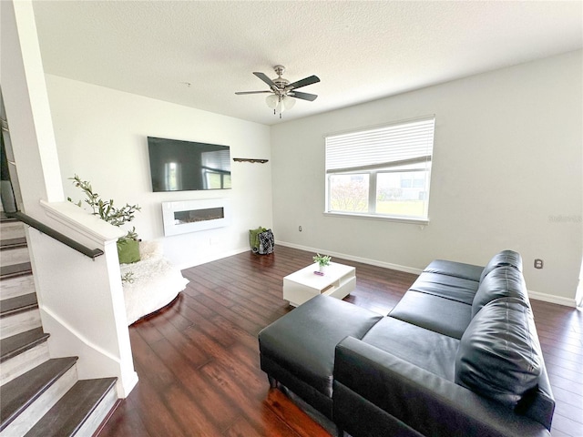 living room with a textured ceiling, ceiling fan, and dark wood-type flooring