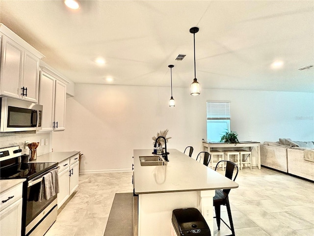 kitchen featuring a breakfast bar, appliances with stainless steel finishes, white cabinetry, and sink