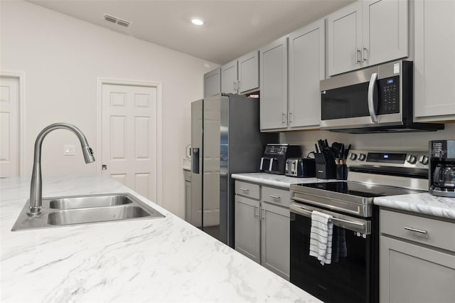 kitchen with gray cabinetry, sink, and stainless steel appliances