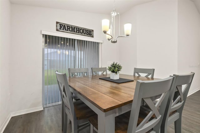 dining space with dark wood-type flooring, lofted ceiling, and an inviting chandelier