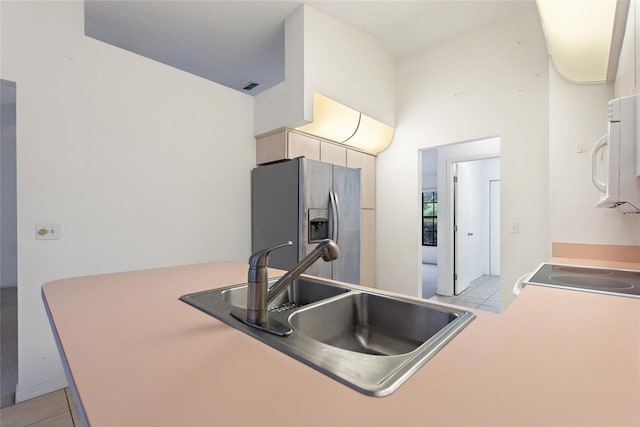 kitchen with stainless steel refrigerator with ice dispenser, sink, and light tile patterned floors