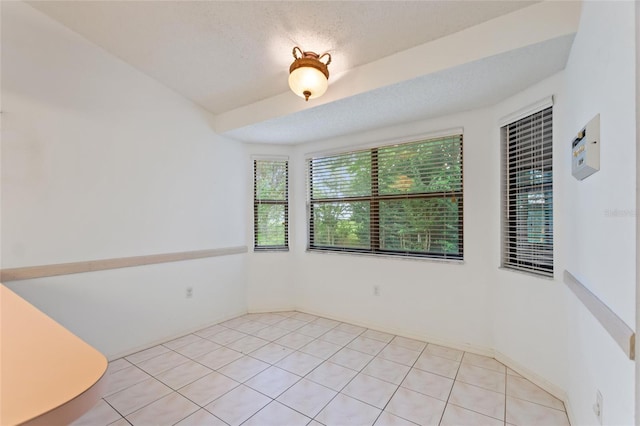 spare room featuring a textured ceiling and light tile patterned floors