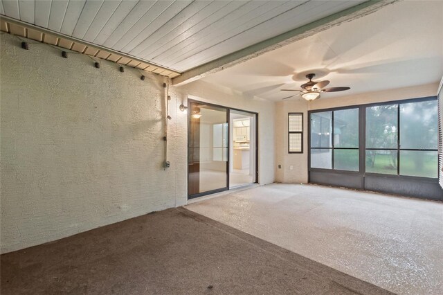 carpeted spare room with beamed ceiling and ceiling fan